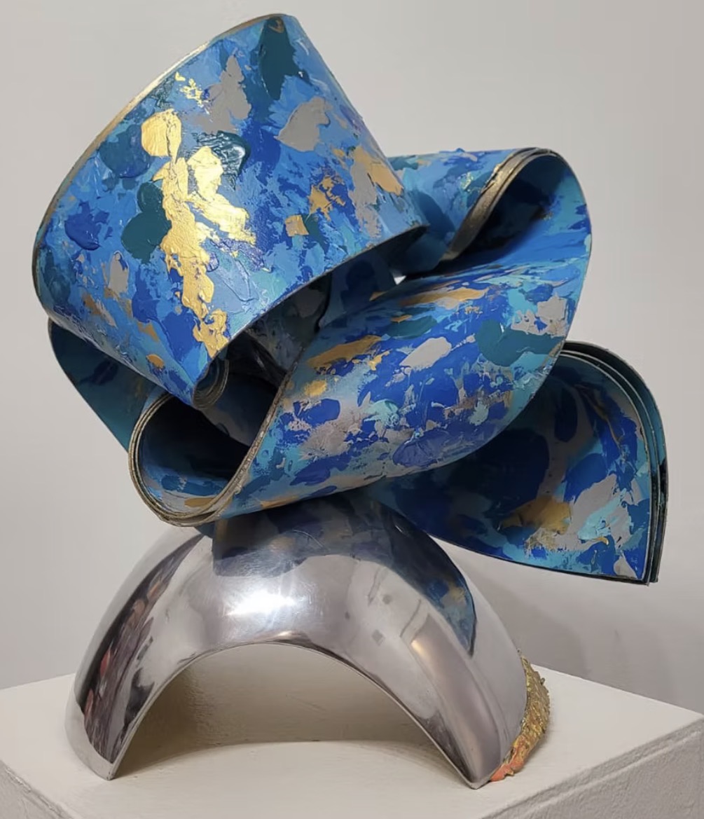 Blue and gold painted sculptural ribbon resting on a polished chrome dome