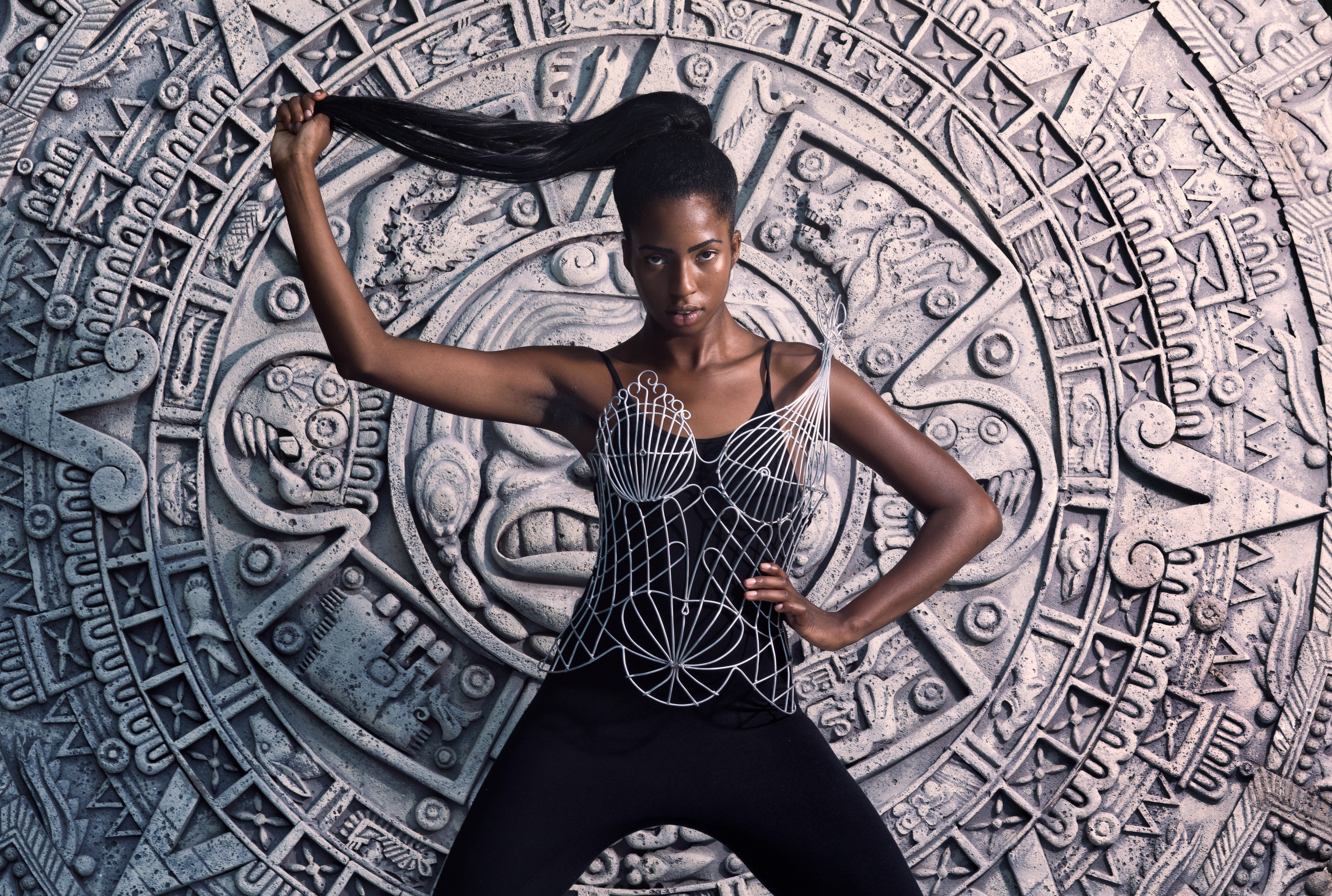 Model wearing sculptural art before an architectural artwork
