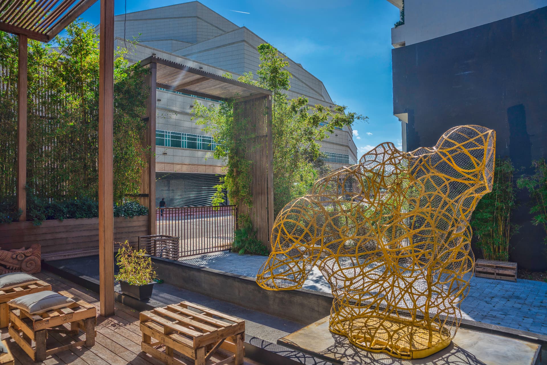 Monumental golden wire sculpture on a sunlit terrace with bamboo garden